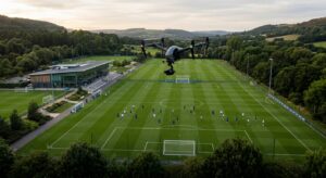 A high-angle cinematic wide shot of a pristine professional football training pitch featuring a slee
